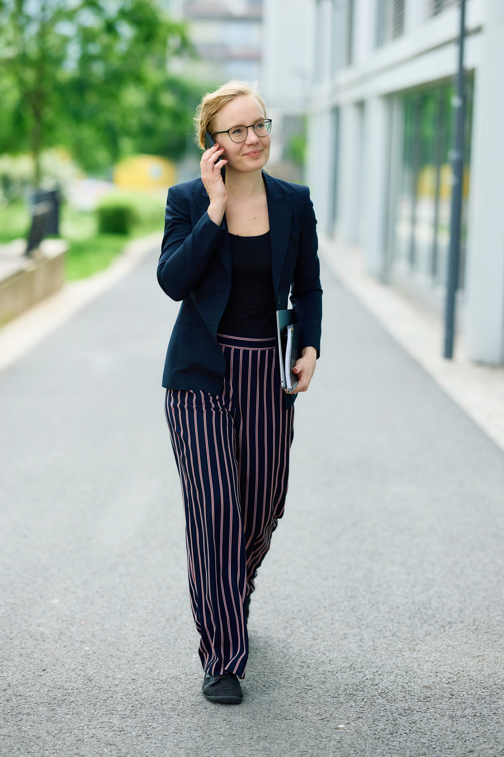 Mareike Walther im Ganzkörperbild, mit natürlichem Licht und einladendem Lächeln beim Telefonieren