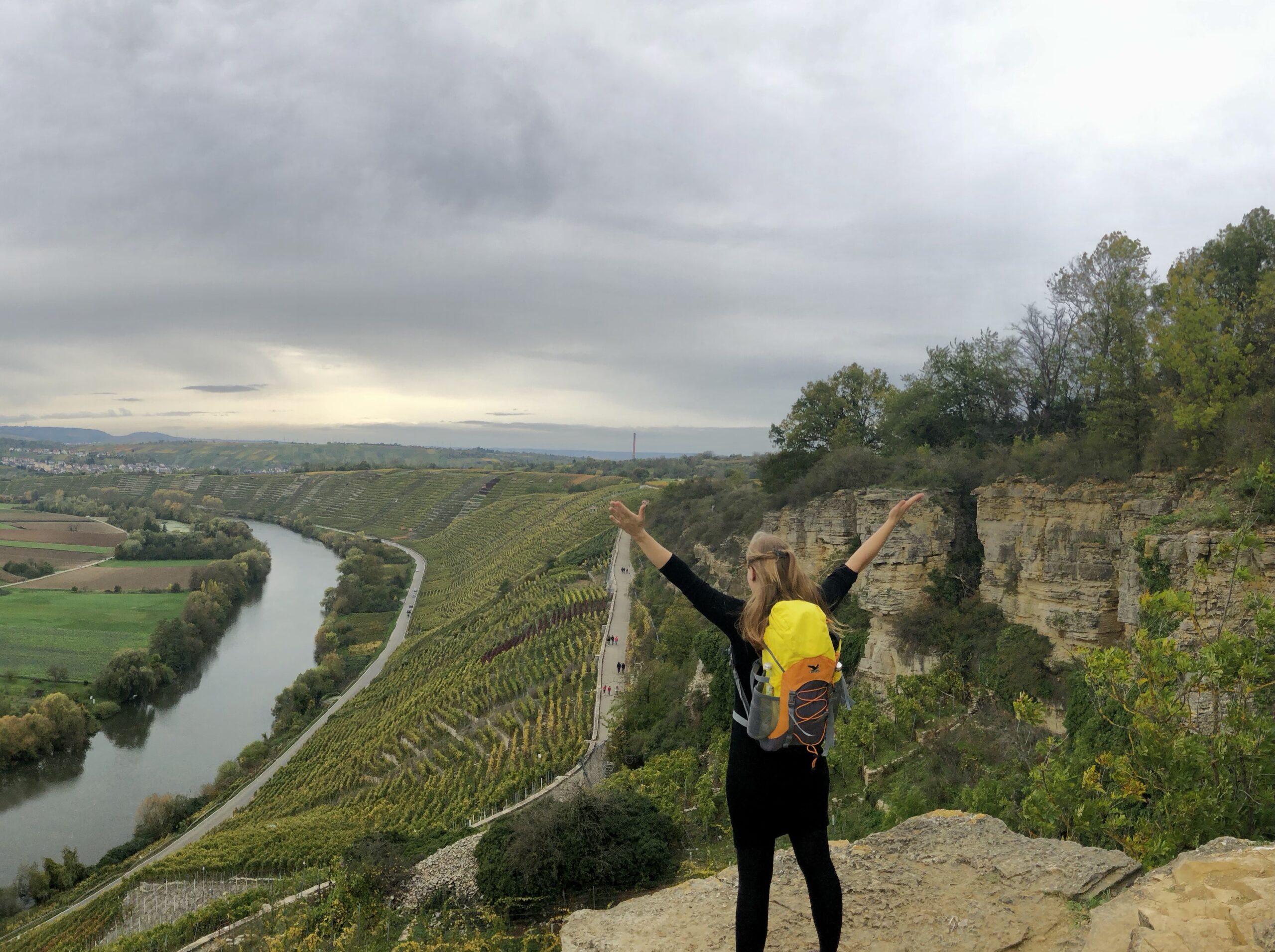 Mareike Walther in Empowerment-Pose auf Felsvorsprung mit Blick über Weinberge